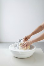 Hands scrubbing clothes with washboard in soapy water